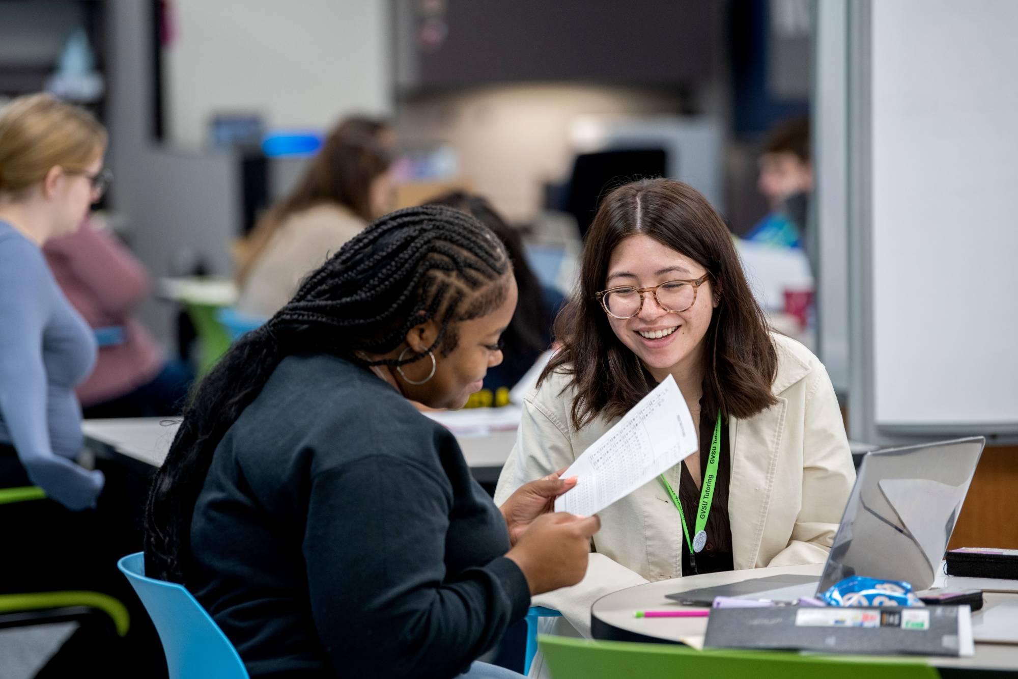 Students smiling at a study table in the tutoring center